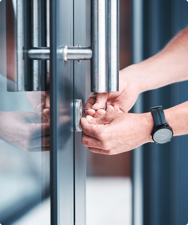Person unlocking glass door with key.