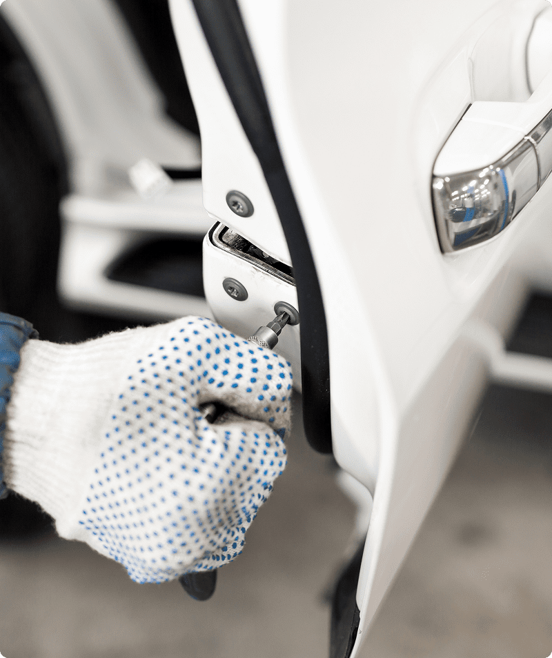 Person tightening car door hinge screw.